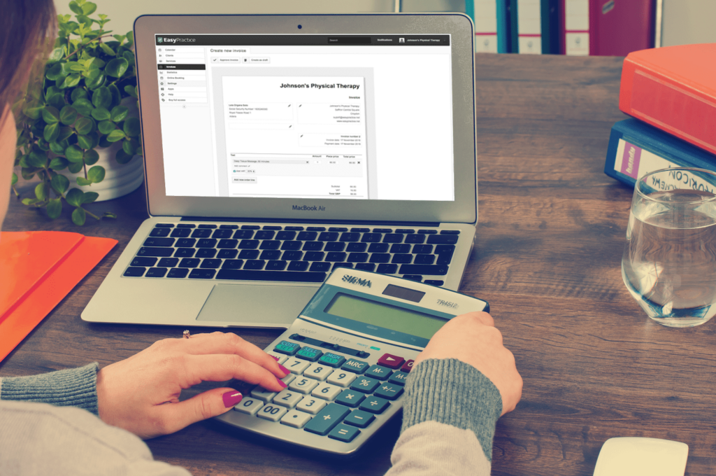 Man using a calculator in front of a laptop