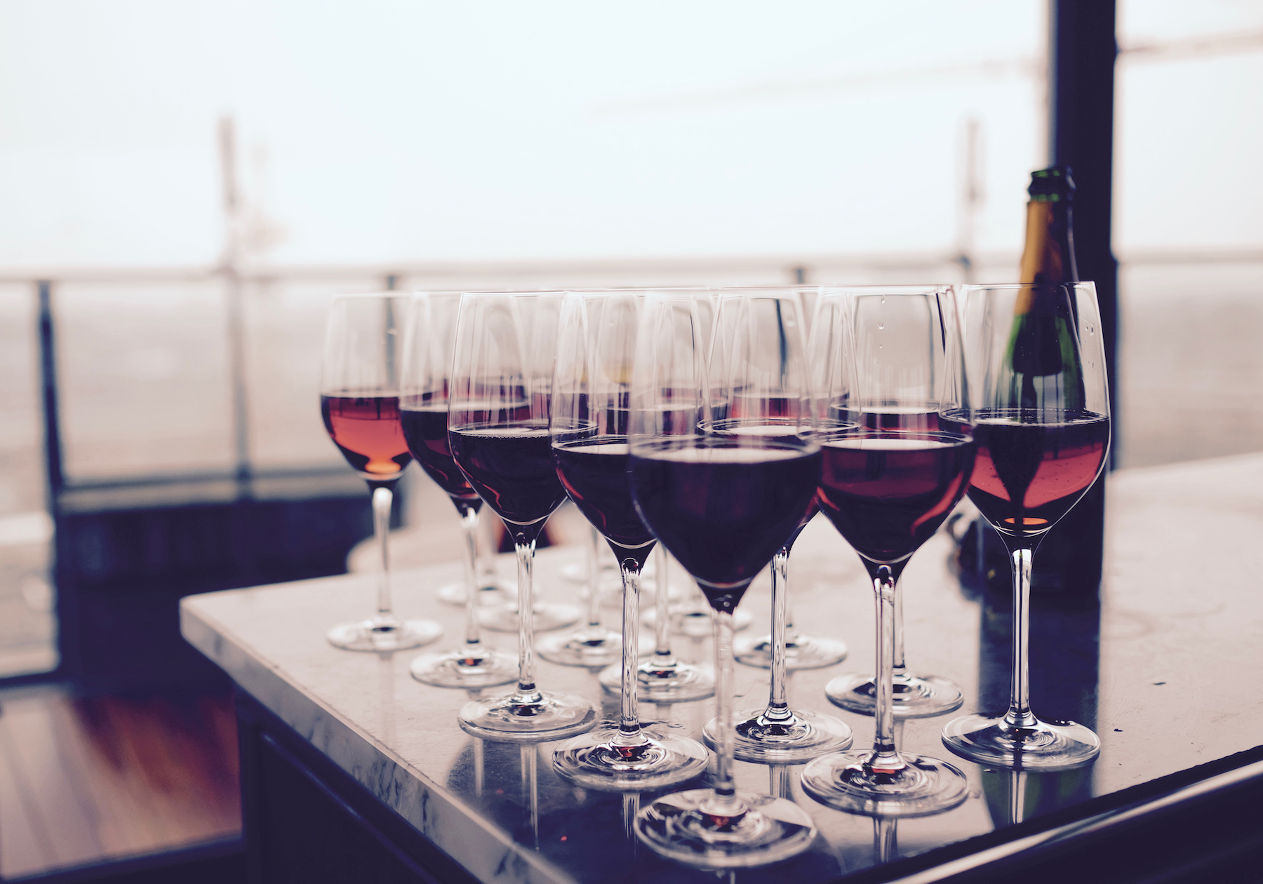 Flera vinglas och en vinflaska uppställda på ett bord som inför ett företagsmingel. 