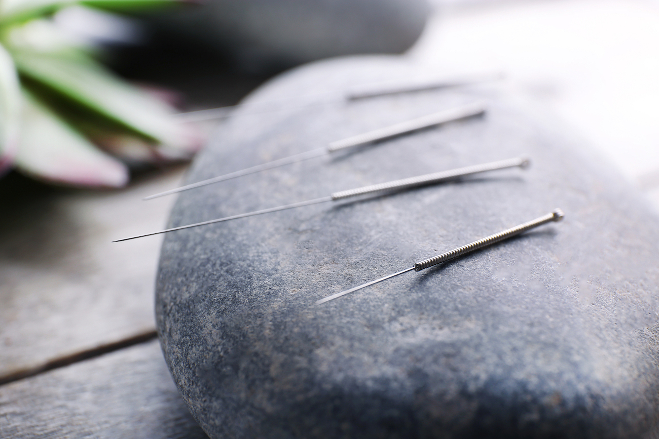 Needle for acupuncture on spa stones on table close up