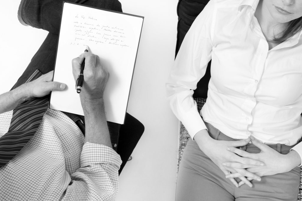 Image of a practitioner with a client during a session. Practitioner is taking notes.