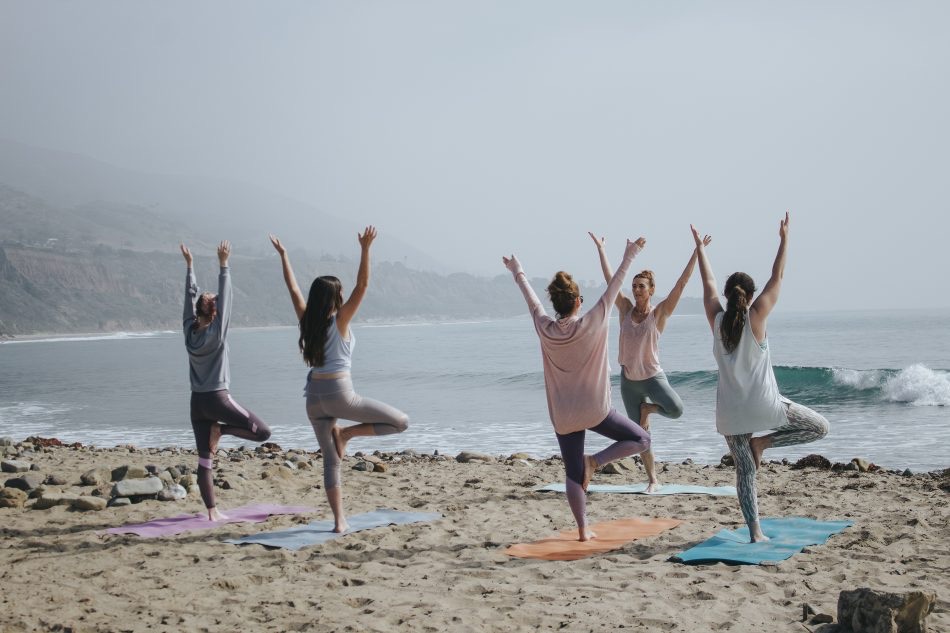 Women doing yoga on the beach in front of waves