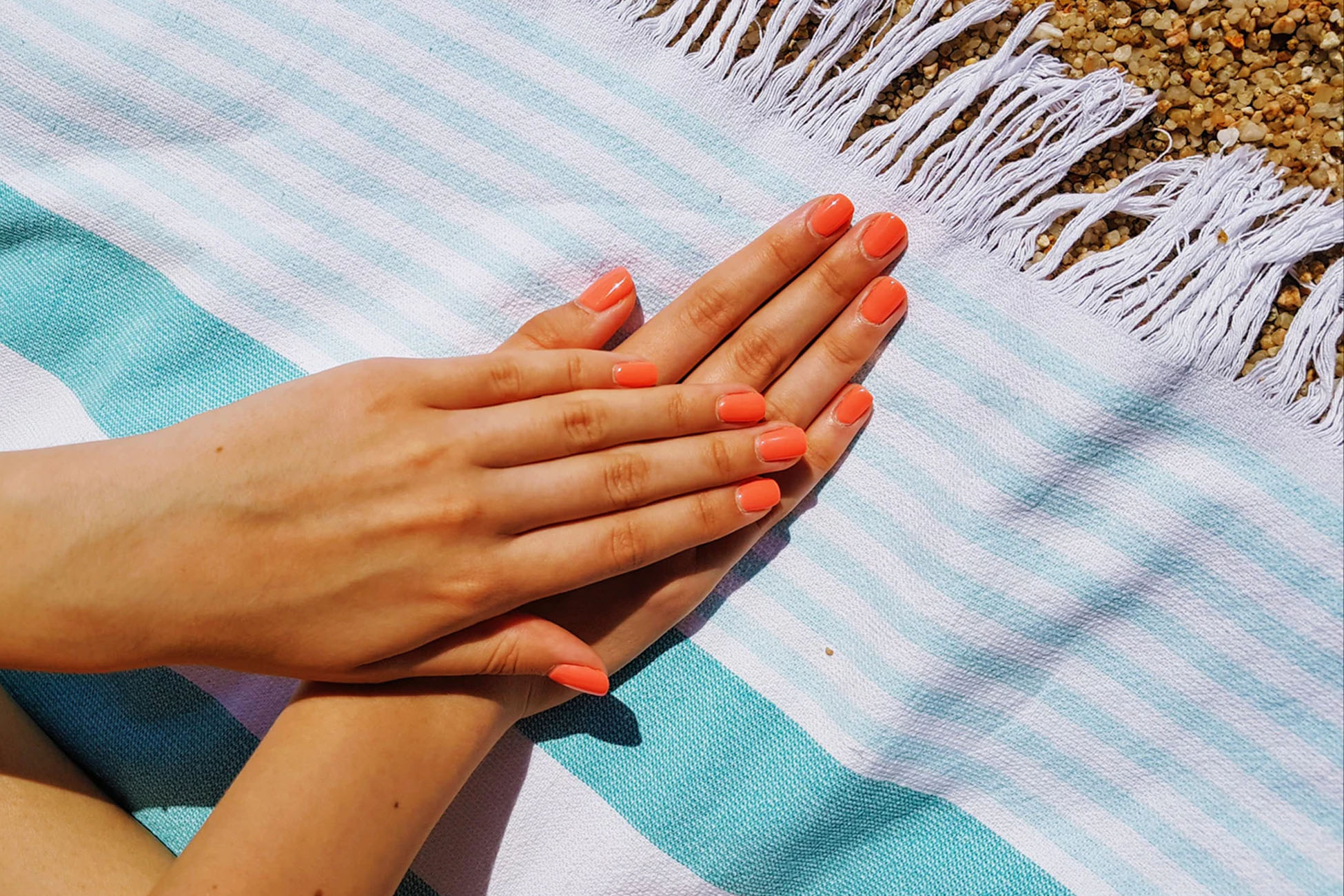 two hands with orange nails on a blue towel