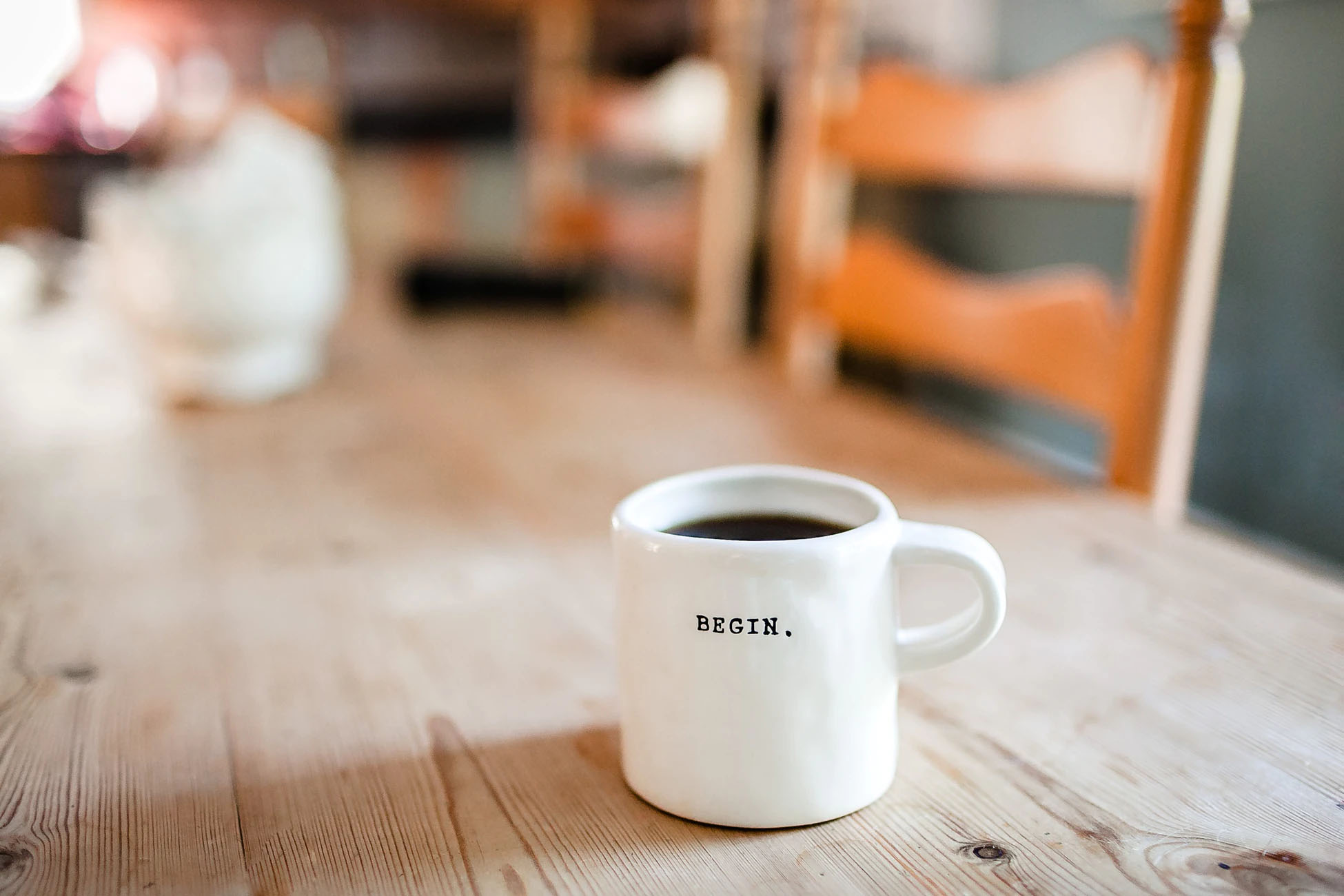 A white cup with coffee that has begin written on it