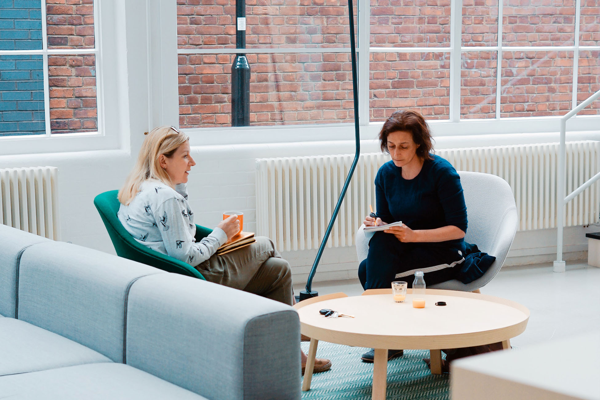 Two women talking and writing things down