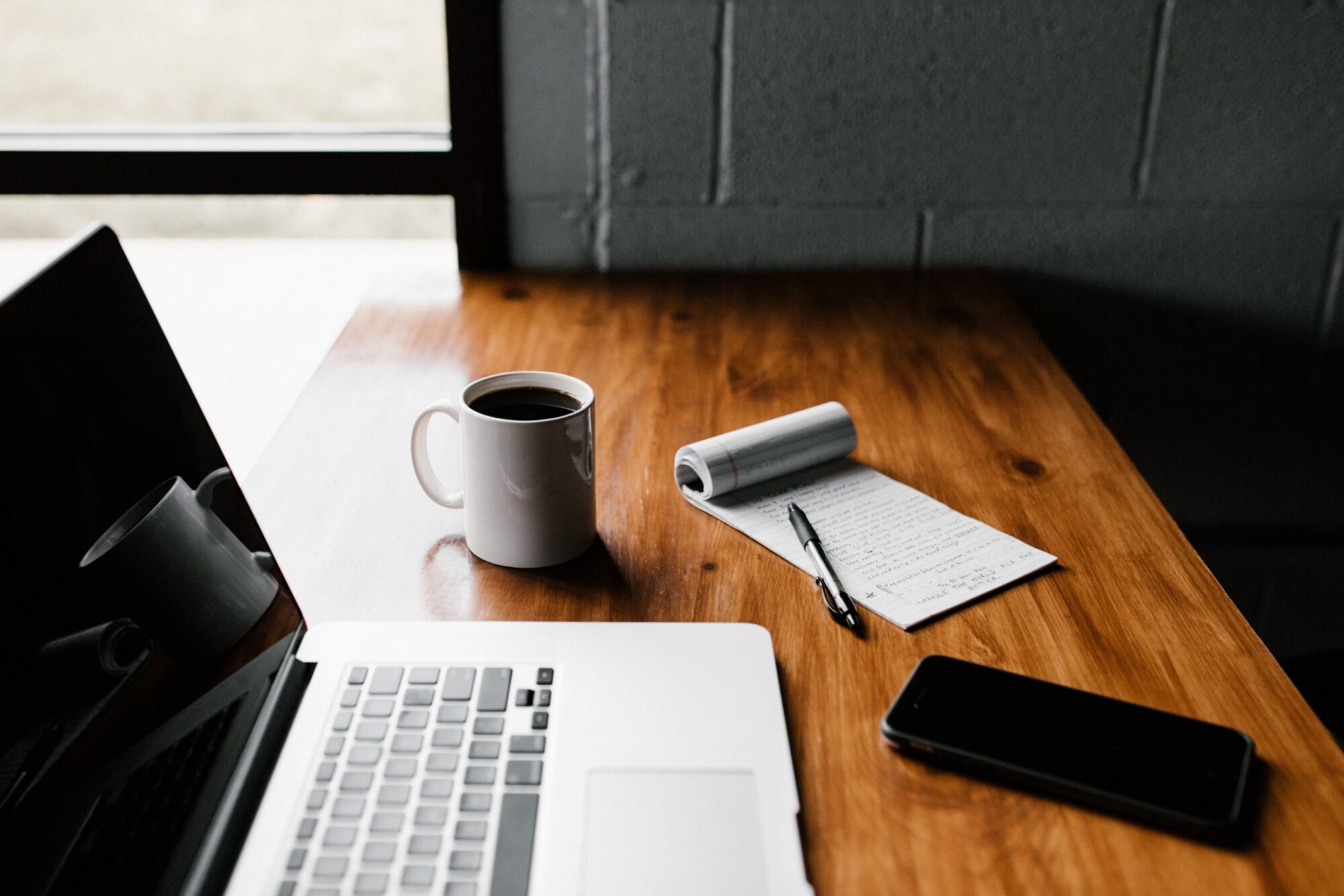 E-consultation workplace with laptop, notebook, smartphone and a cup of coffee on it