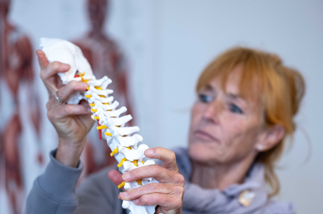 Physiotherapist & sports medicine expert Gitte Vestergaard holding a model of a spine