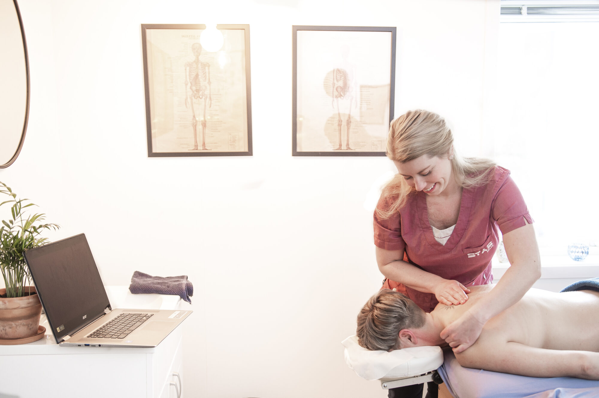 Kvinna står i sitt kontor och ger massage till en man på ett massagebord