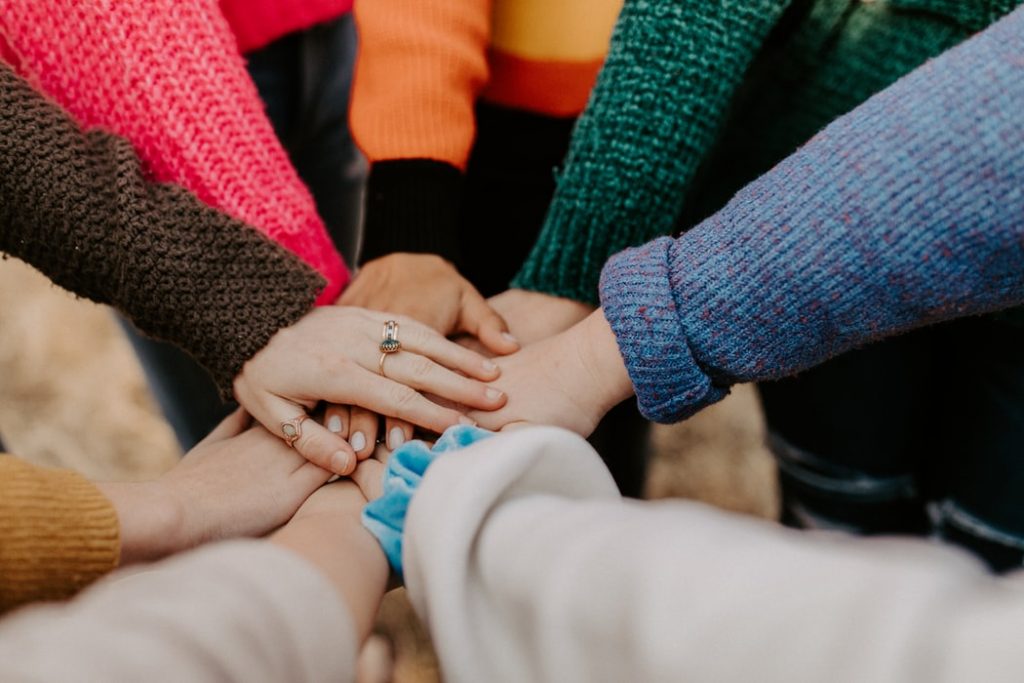 People stood in a circle with their hands on each others.