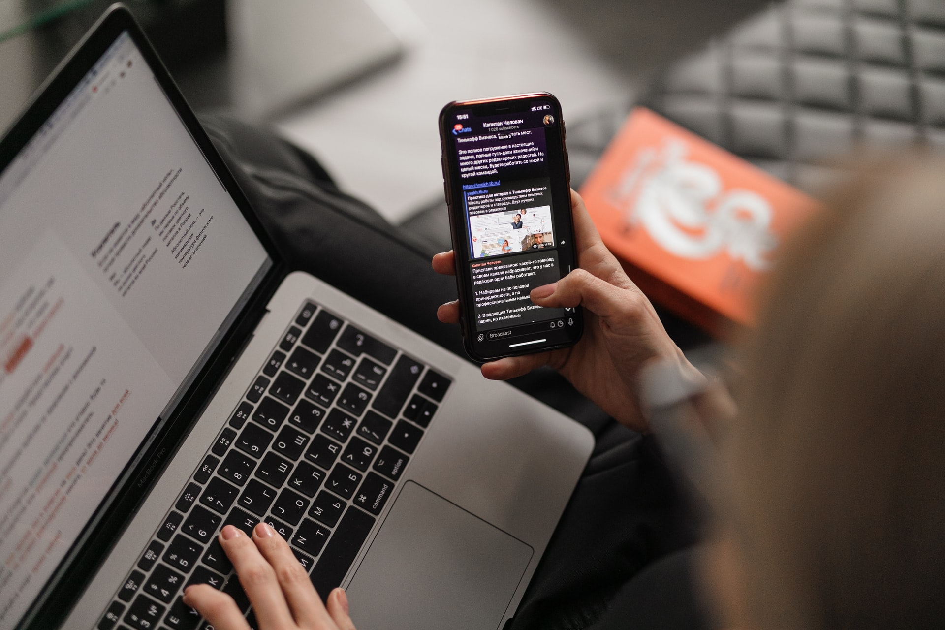 A person reading messages on phone while working on a laptop