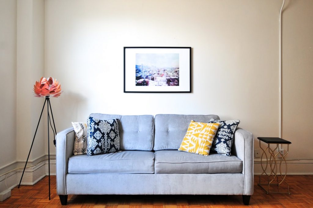 A sofa in a room with a picture behind it.