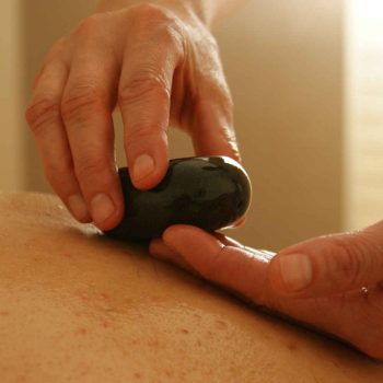 Matthew Clark providing a massage treatment called hot-stones to a patient