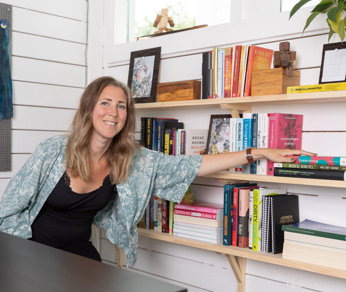 Maria Särén inne på sitt kontor med handen på en bokhylla