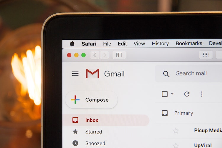 Image of a laptop displaying the Gmail website. In the background is an open fire.
