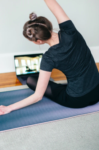 Tjej som sitter och gör yoga genom en video på en dator