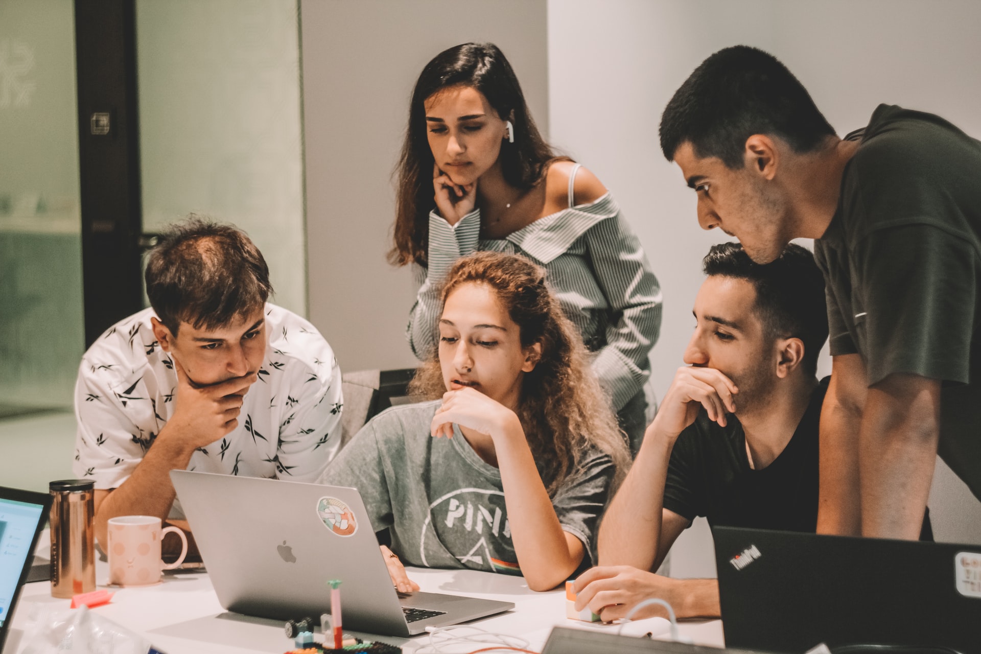 Several people in front of a laptop and sharing their opinions