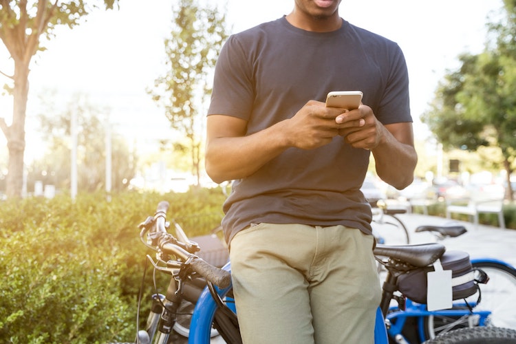Man with phone leaning on a bike