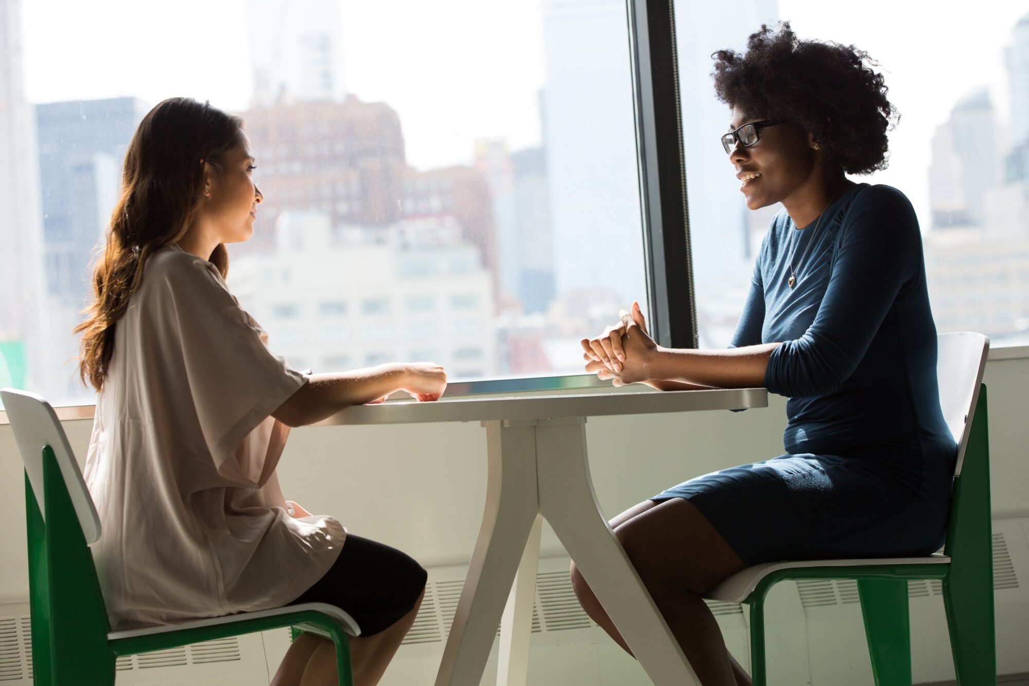 two women sitting at a table talking and smiling