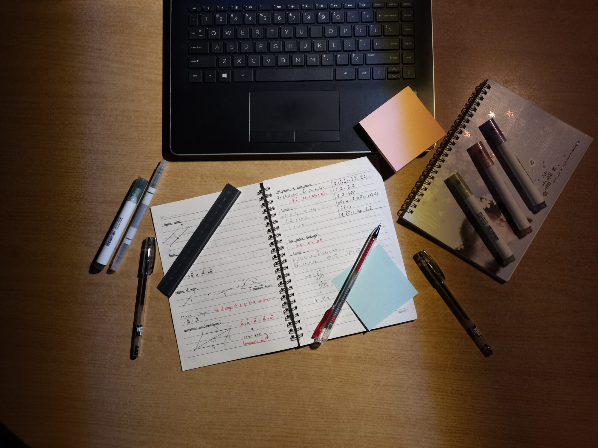 En pc og en notatbok med penner