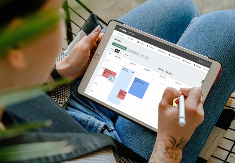 Dame som holder en tablet som viser EasyPractices online dagboksystem