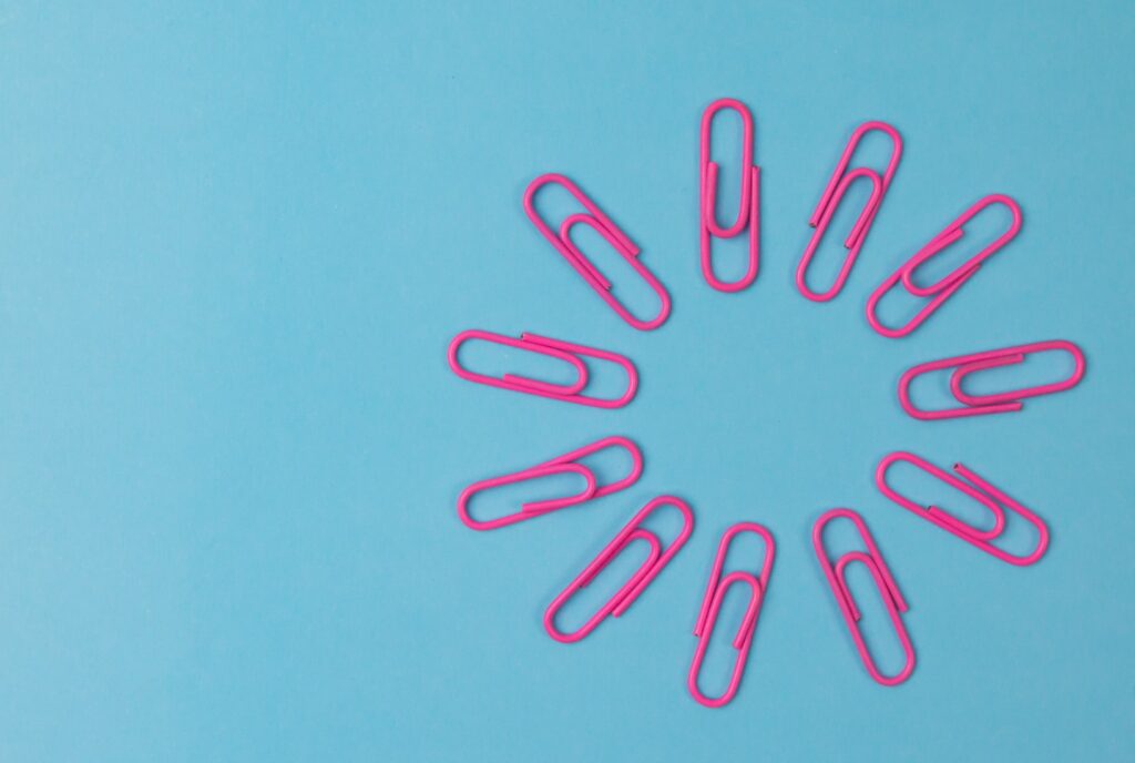 Composition of pink paper clips isolated on blue background