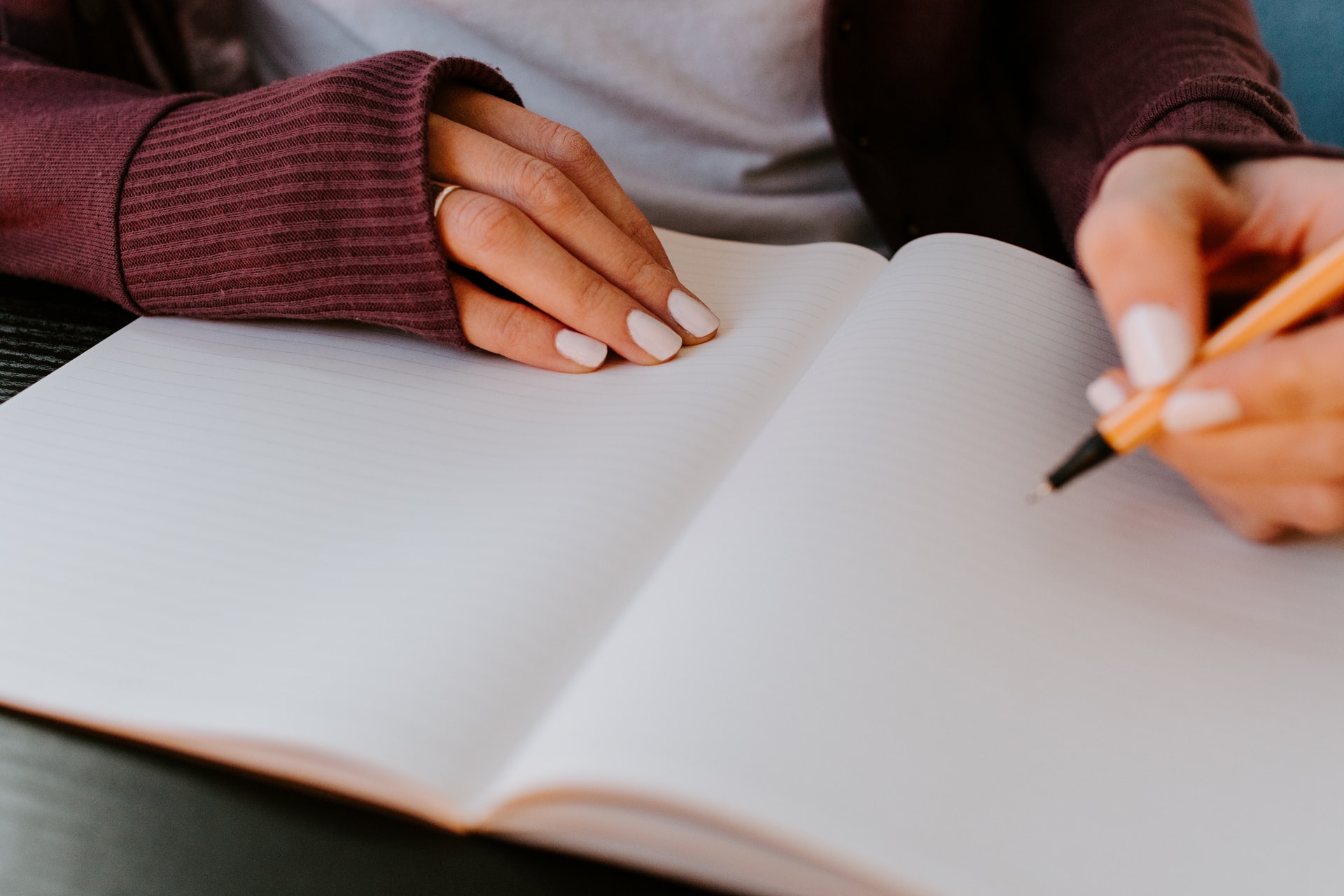 Woman's hands at a desk writing in a blank notebook