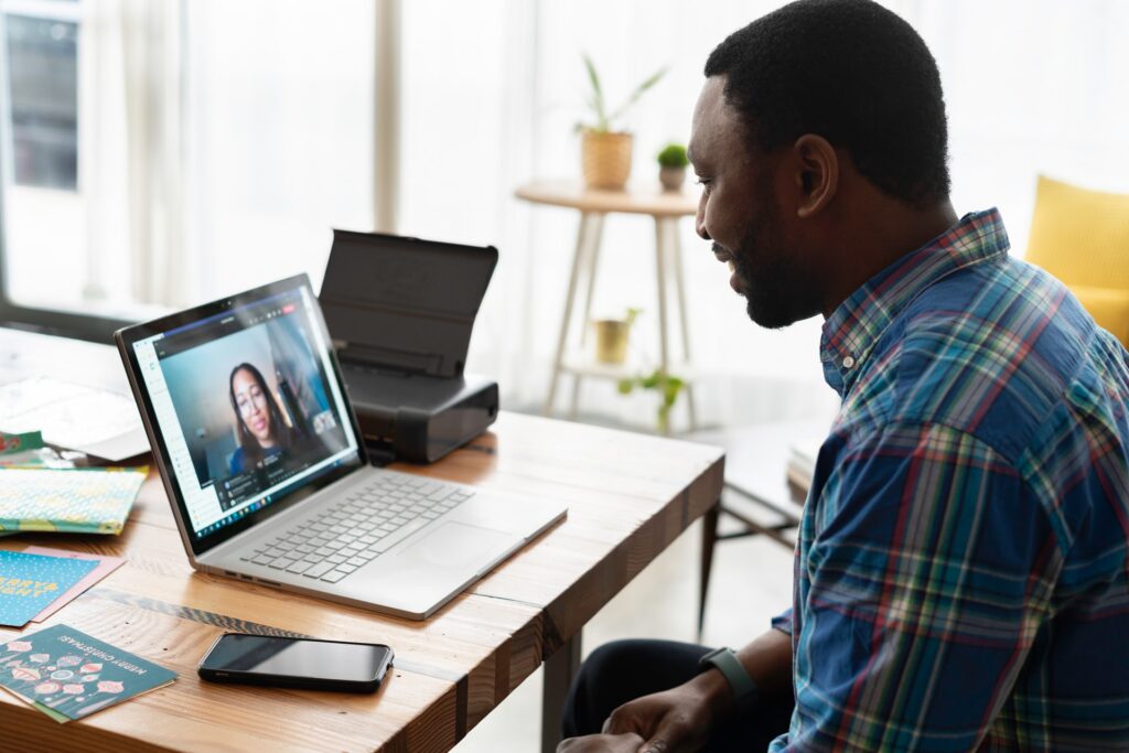 En mann som sitter bak en pc-skjerm i et videomøte med en dame. 