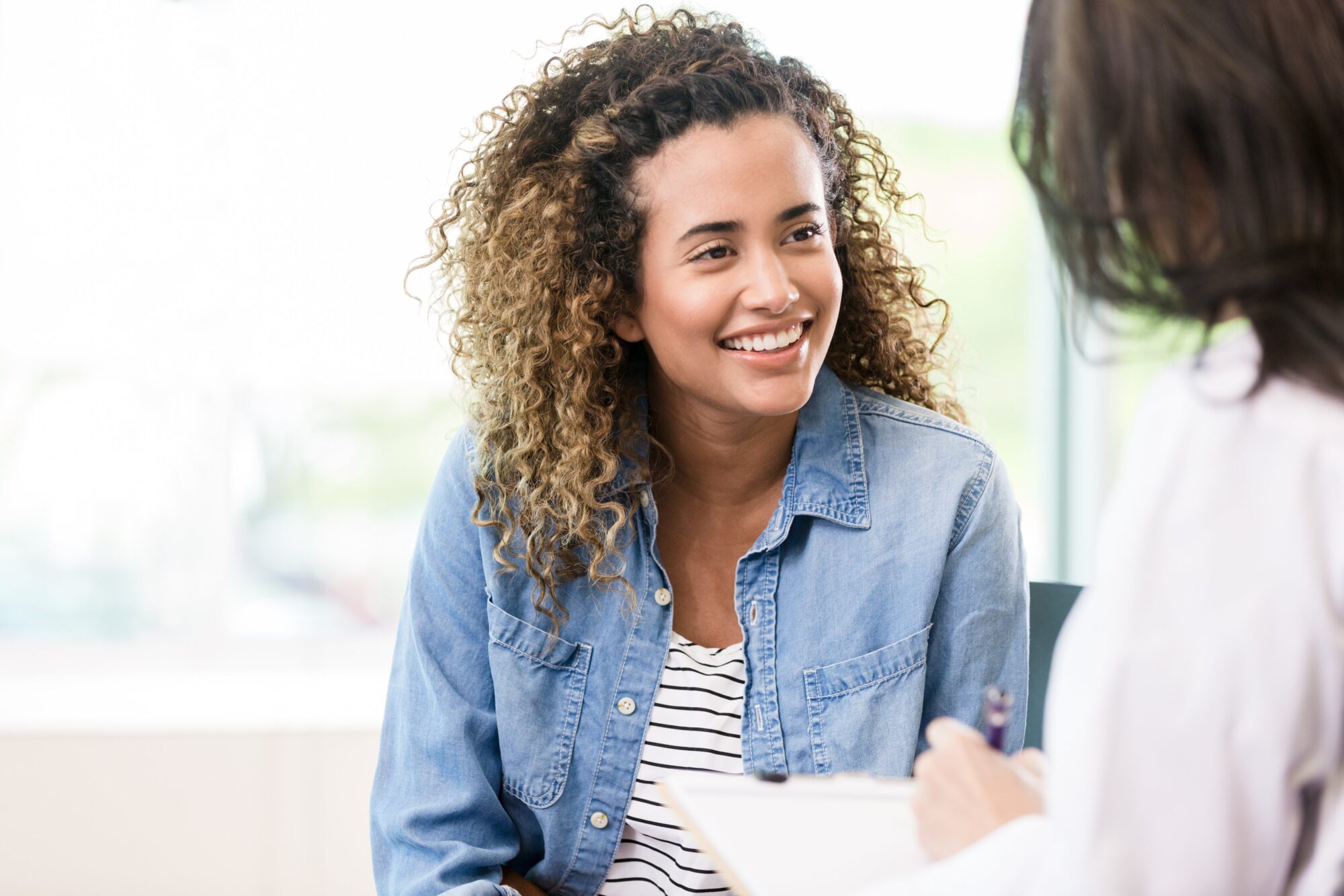 A smiling female patient attentively listens as a doctor