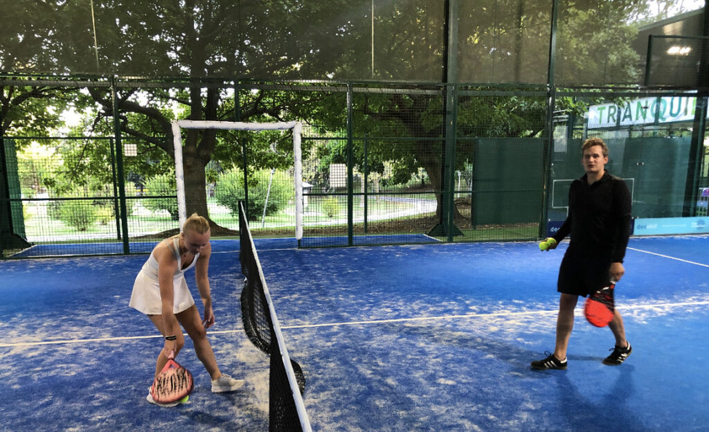 Padel match mellom Emil og Pia på en utendørs padelbane under tak