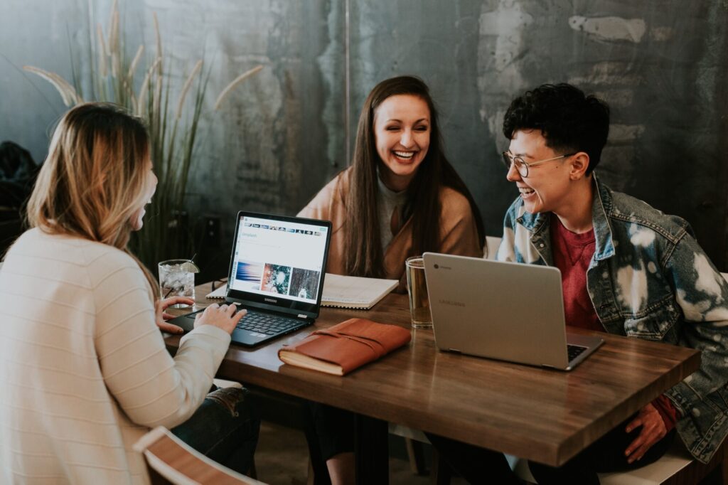 Three people sitting together a at table with their computers, and learning from eachother