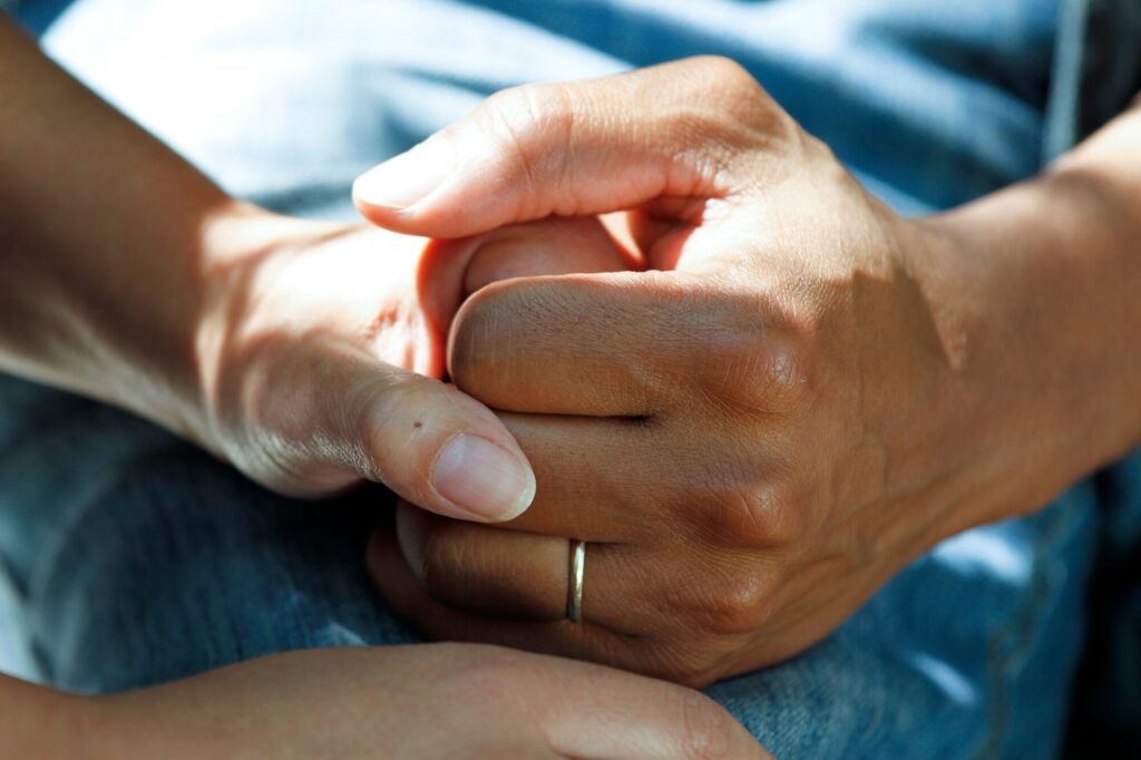 Two people holding hands for comfort